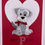 Thumbnail: Card with pearlized dog brooch wearing a red scarf on embossed heart background, with the sentiment “Have a pawsome day.”
