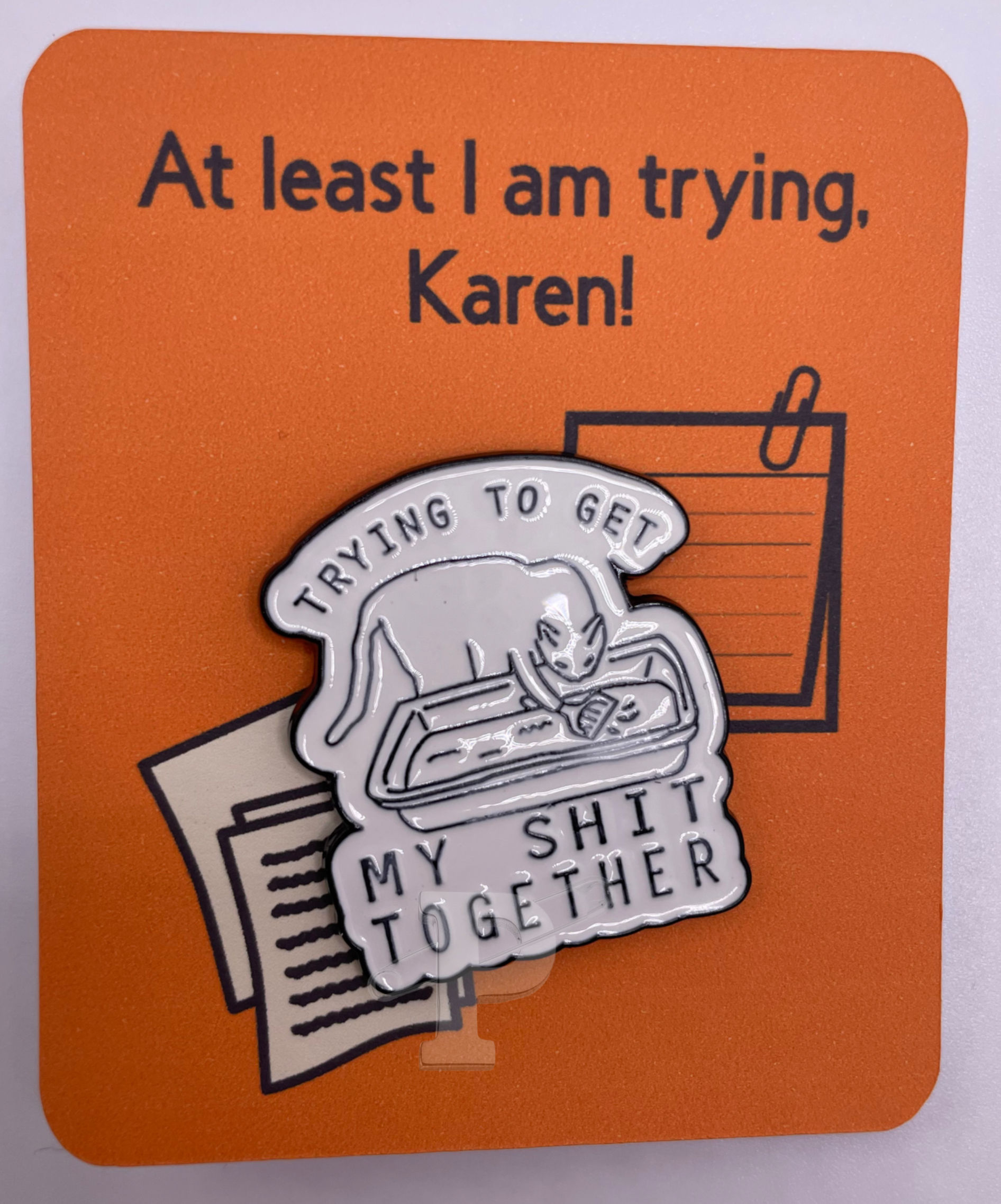 A flat card that says "At least I'm trying, Karen" with a pin attached that says "Trying to get my shit together"