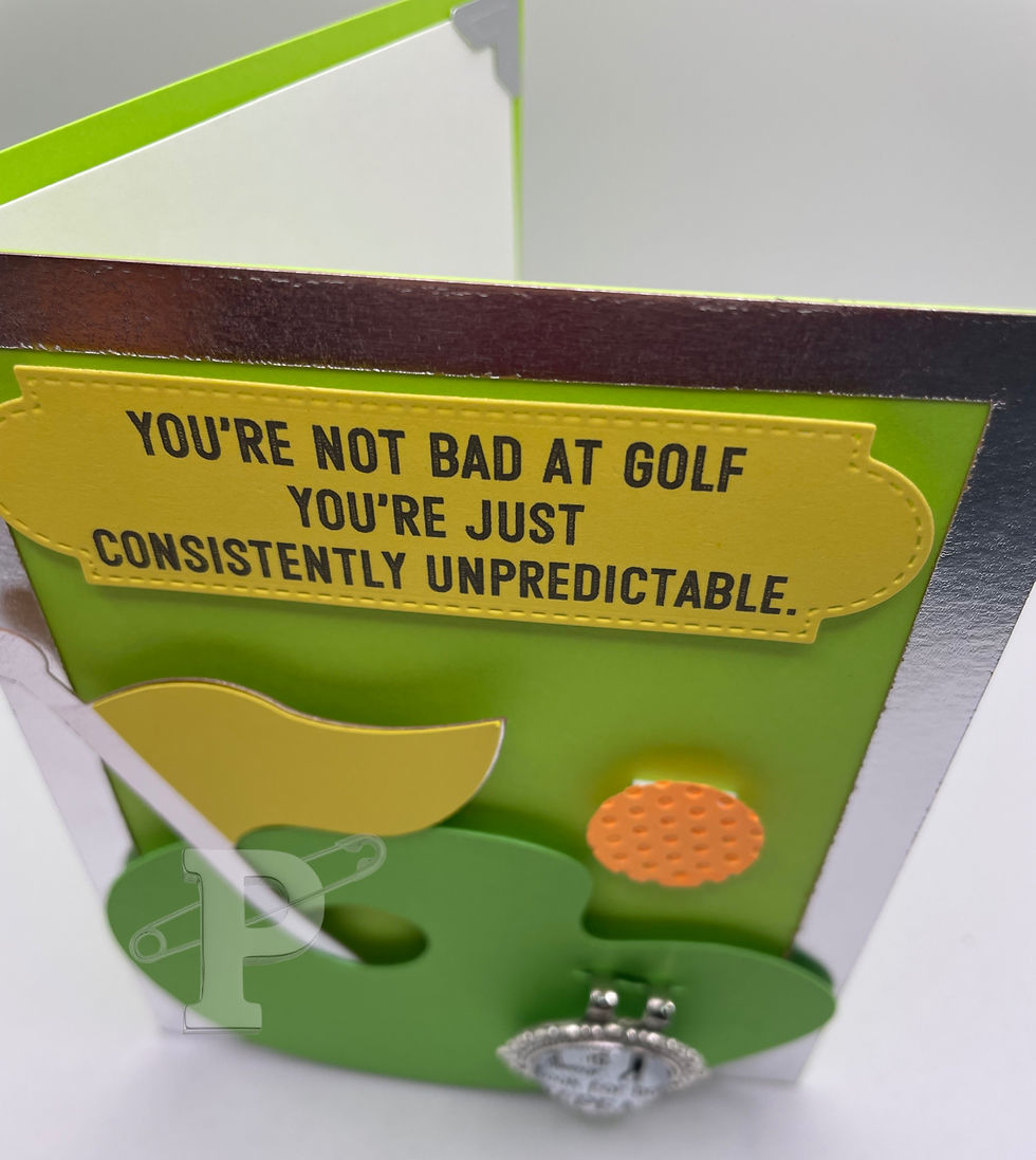 Top view of golf card with detachable magnetic ball marker reading “Swing. Swear. Look for ball. Repeat.” and hat clip.