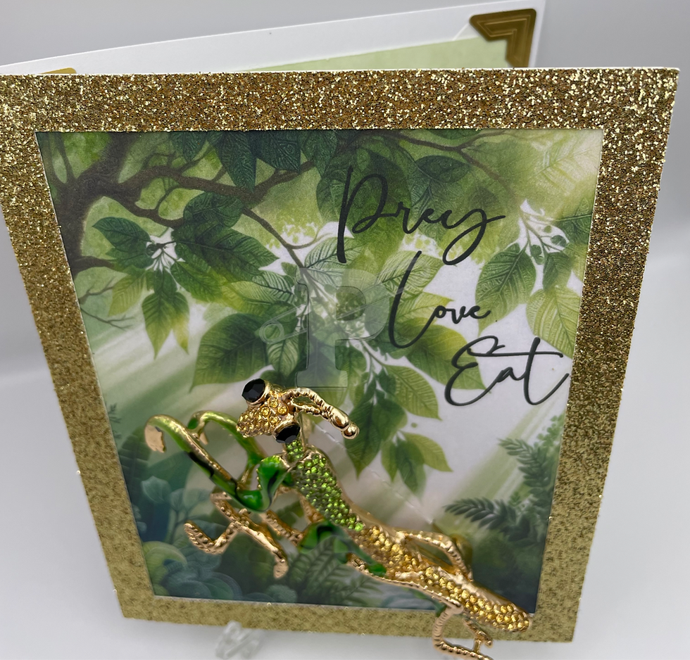Greeting card with large praying mantis brooch in greenery and the sentiment “Prey. Love. Eat.”