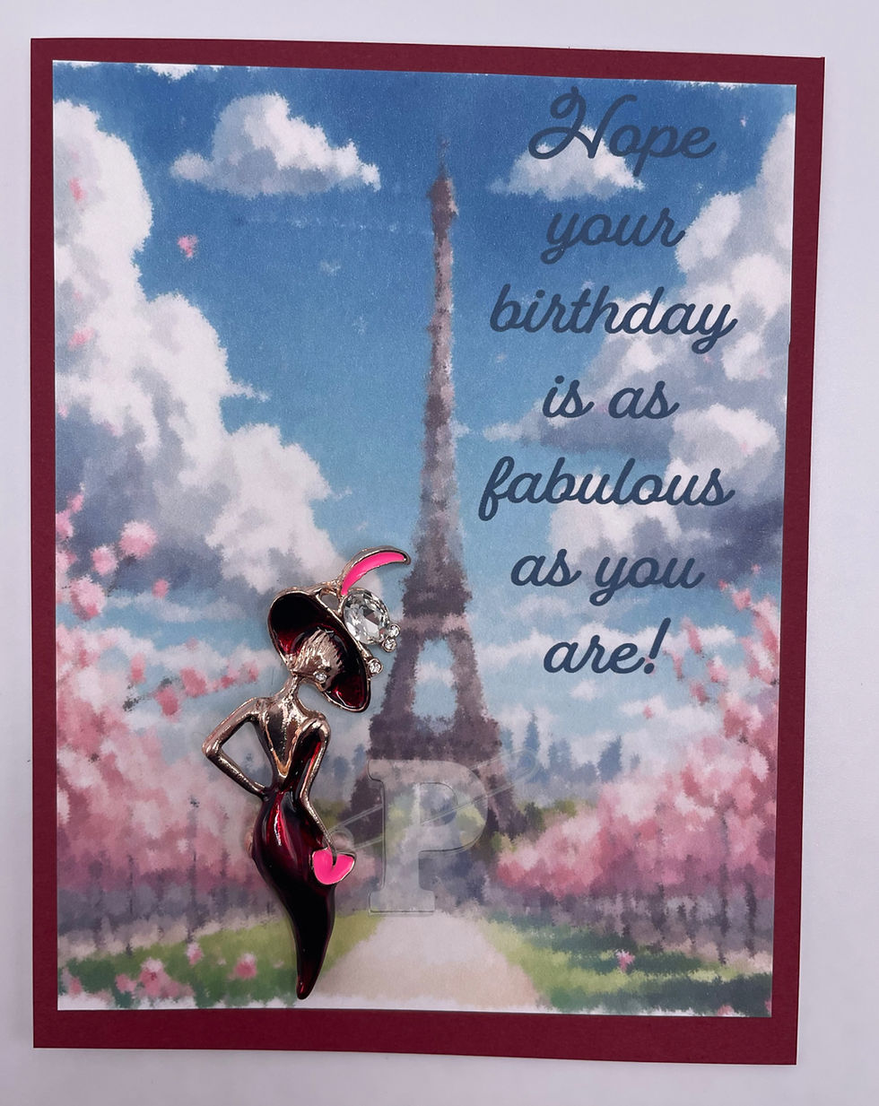 Thumbnail: Fashion-themed greeting card with brooch of woman in red dress near Eiffel Tower.