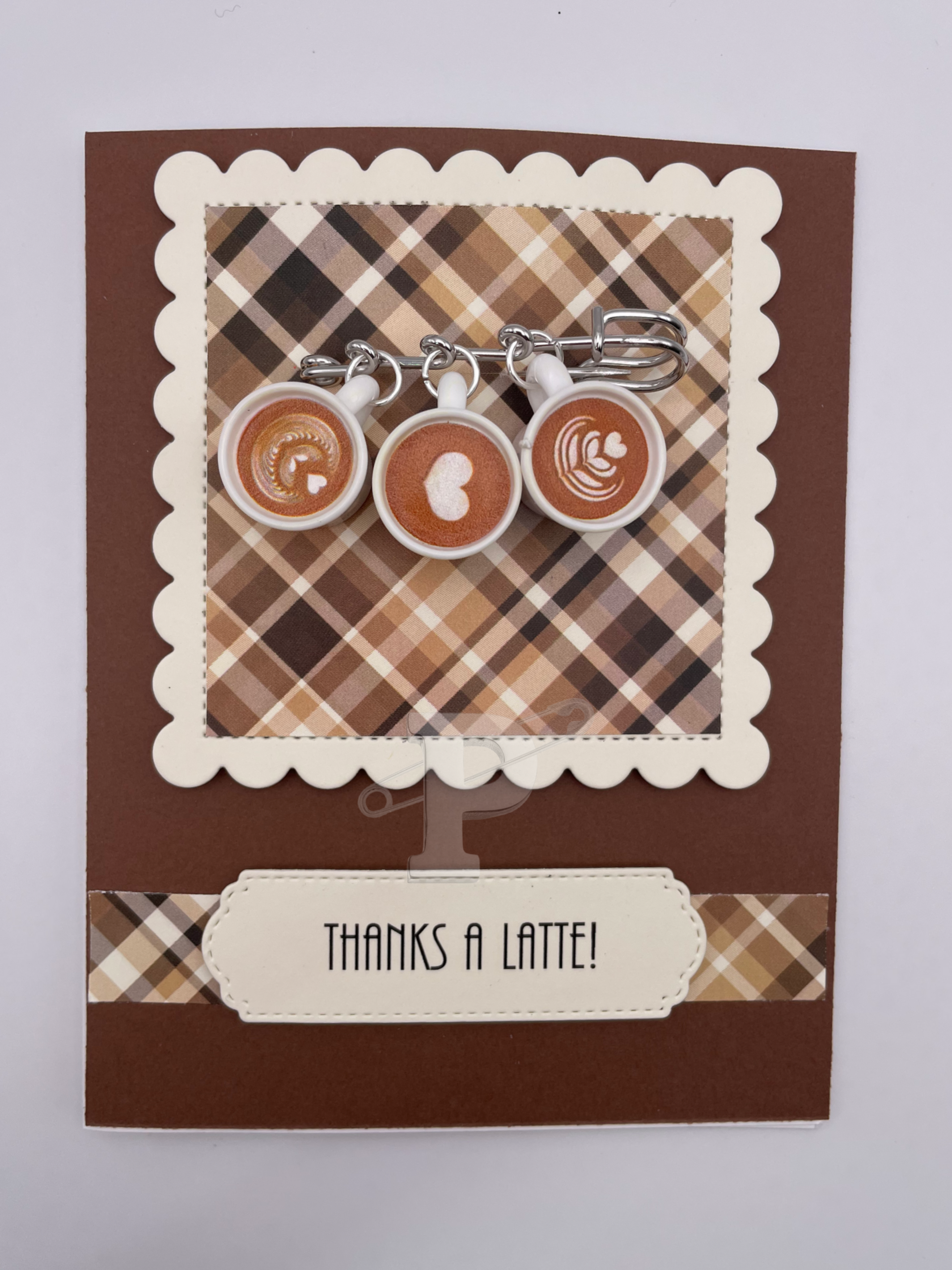 Greeting card with brooch featuring three miniature coffee cups with heart-shaped swirls, sentiment "Thanks a latte"