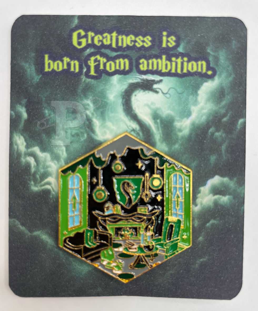 Flat card that reads “Greatness is born from ambition” with Slytherin common room enamel pin attached.