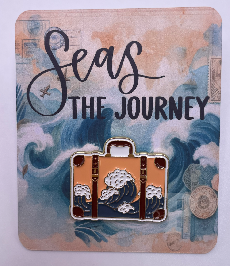A flat card that reads ‘Seas the Journey’ with an enamel pin shaped like a peach suitcase featuring ocean waves.
