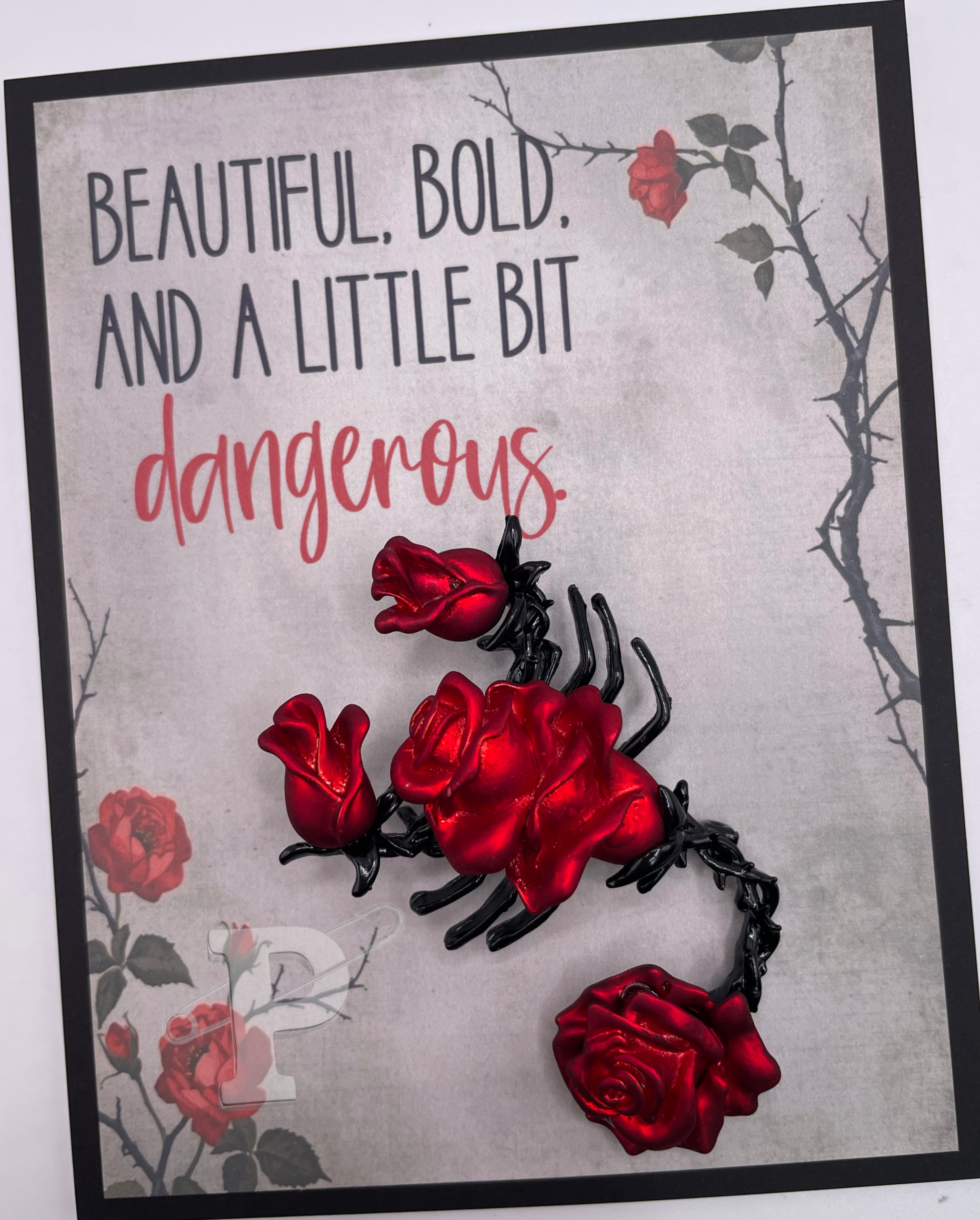 Greeting card that reads “Beautiful, bold, and a little bit dangerous” with black and red rose scorpion brooch