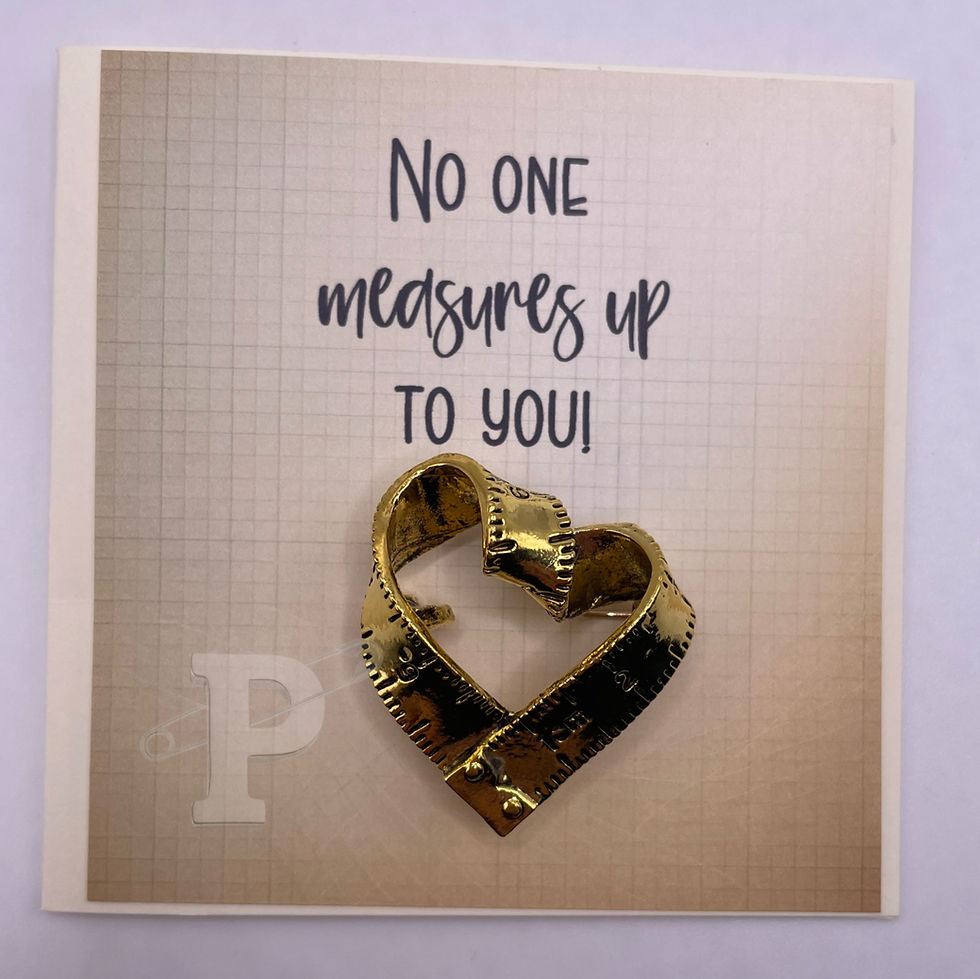Mini card that reads “No one measures up to you!” with gold measuring tape heart brooch attached.