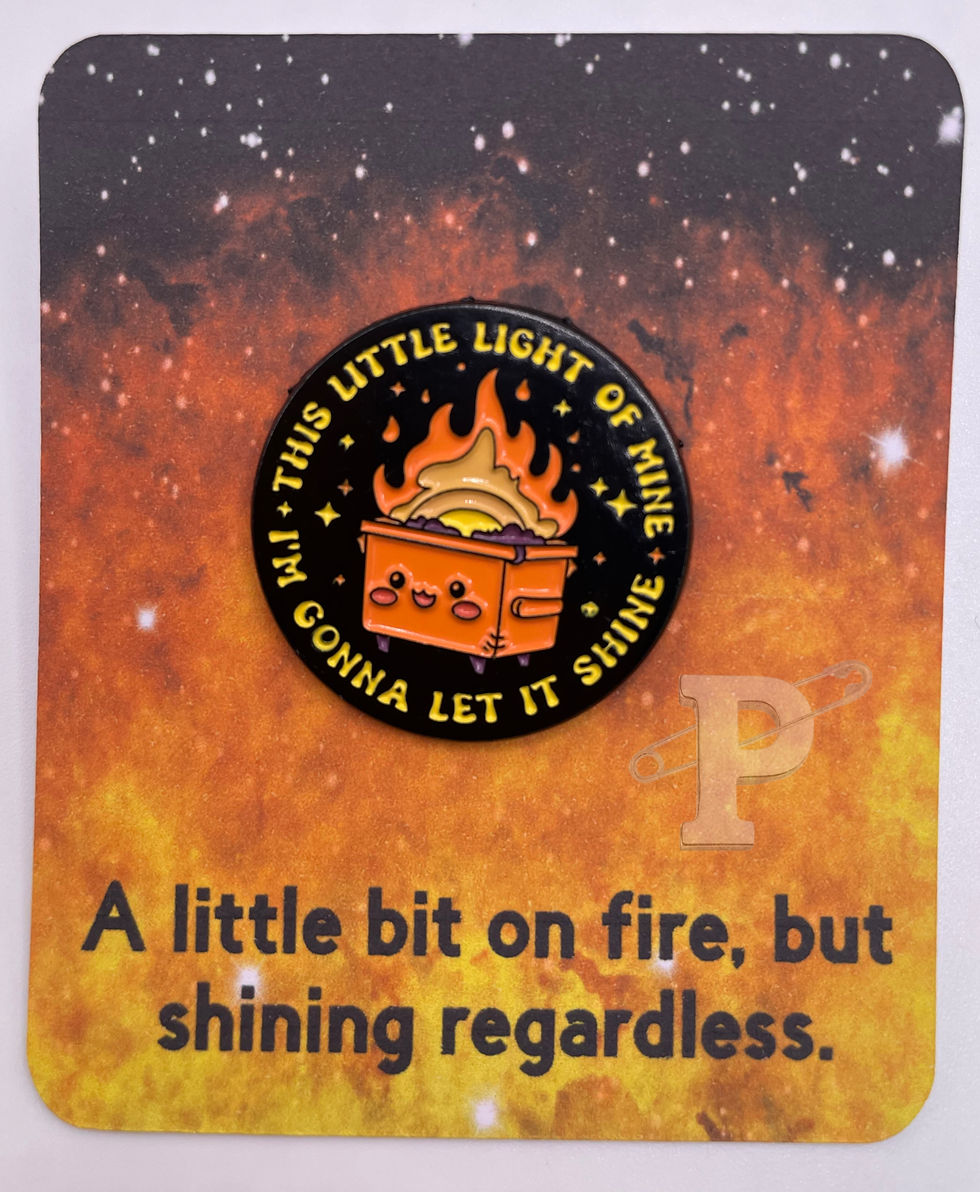 Flat card that reads "A little bit on fire..shining regardless" with dumpster fire pin “This little light of mine.”