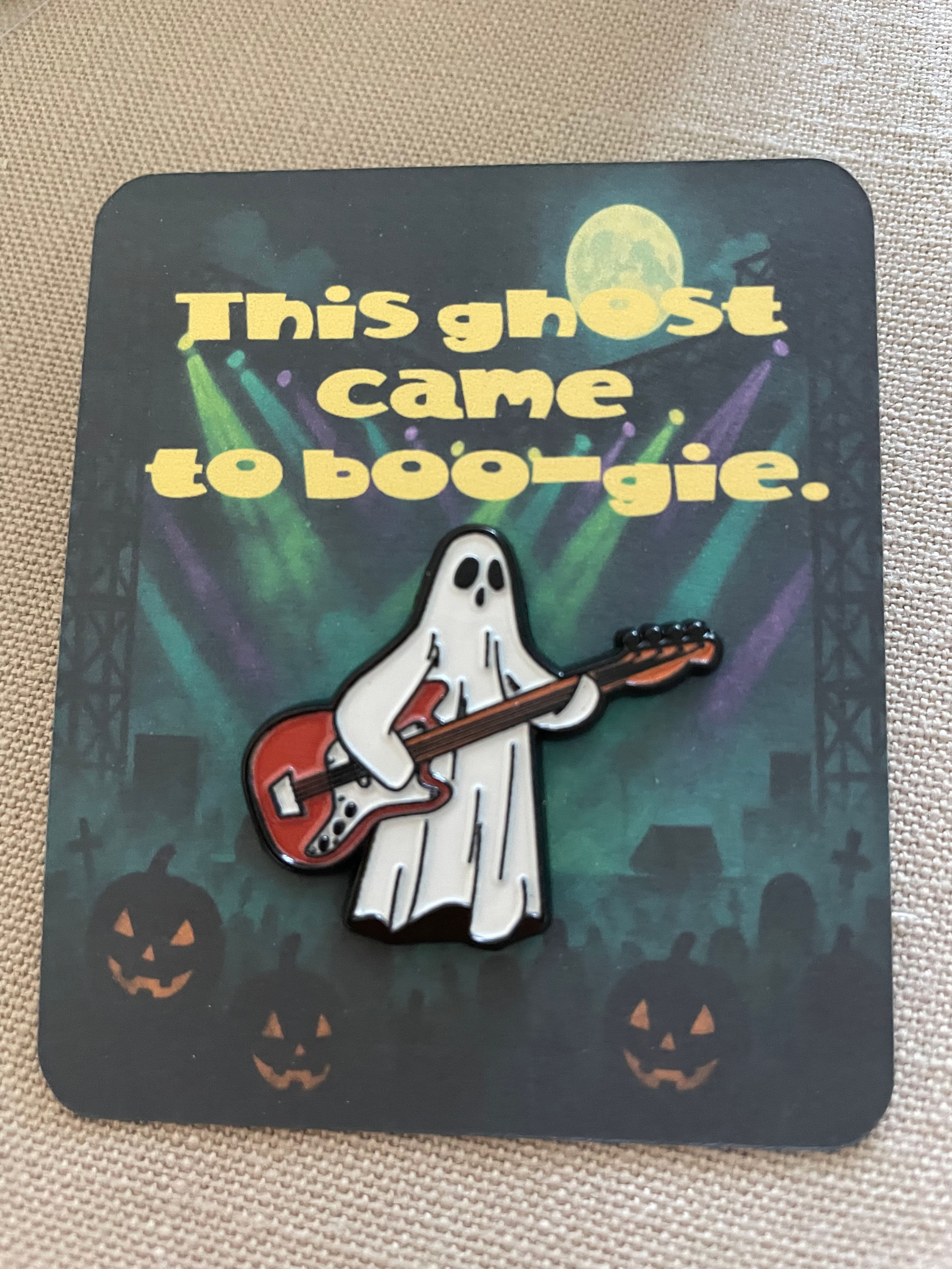 A flat card that reads "This ghost came to boogie" with a ghost playing a guitar pin attached.