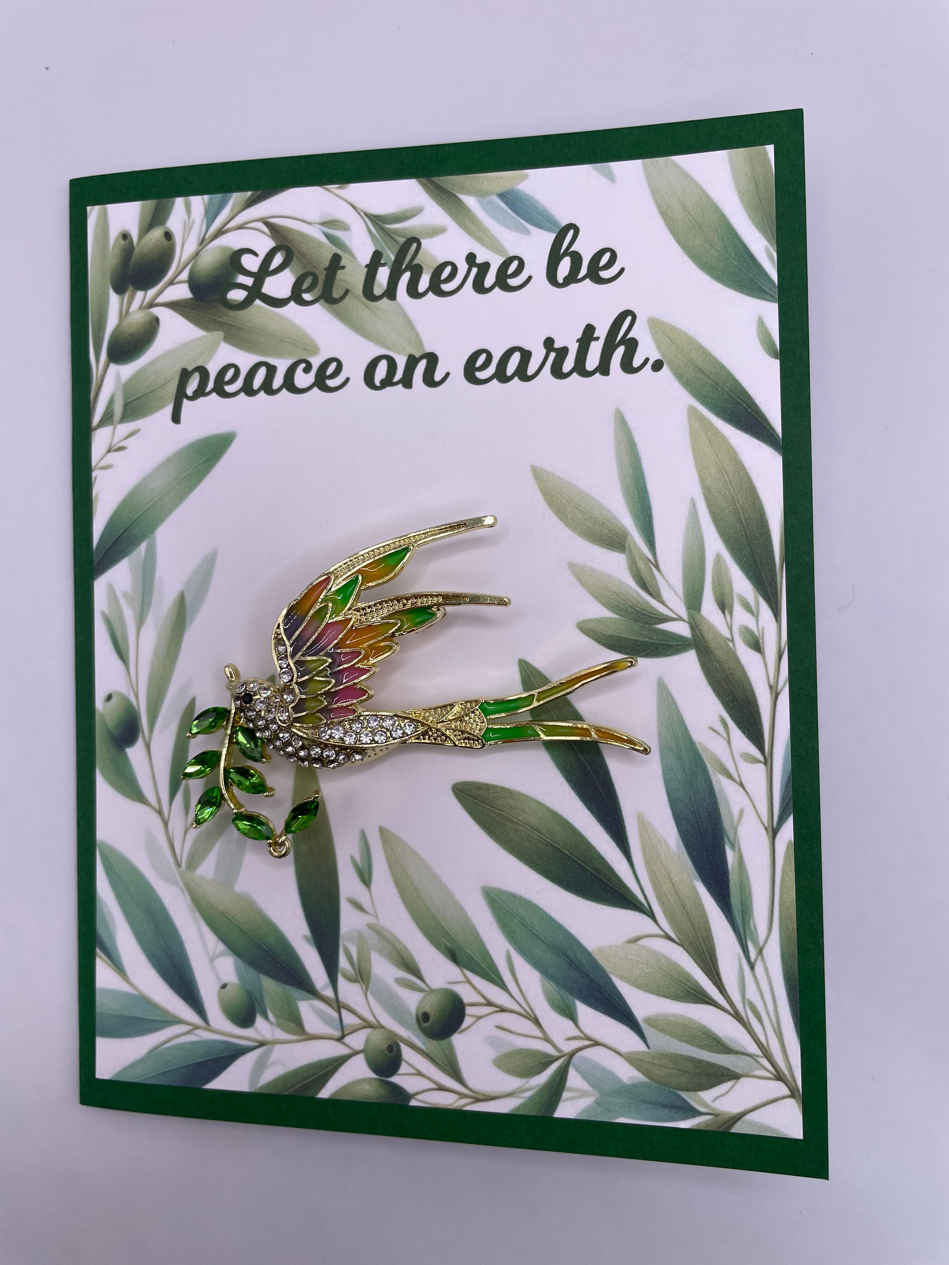 A Christmas card that reads "Let there be peace on earth" with a dove holding an olive branch brooch attached