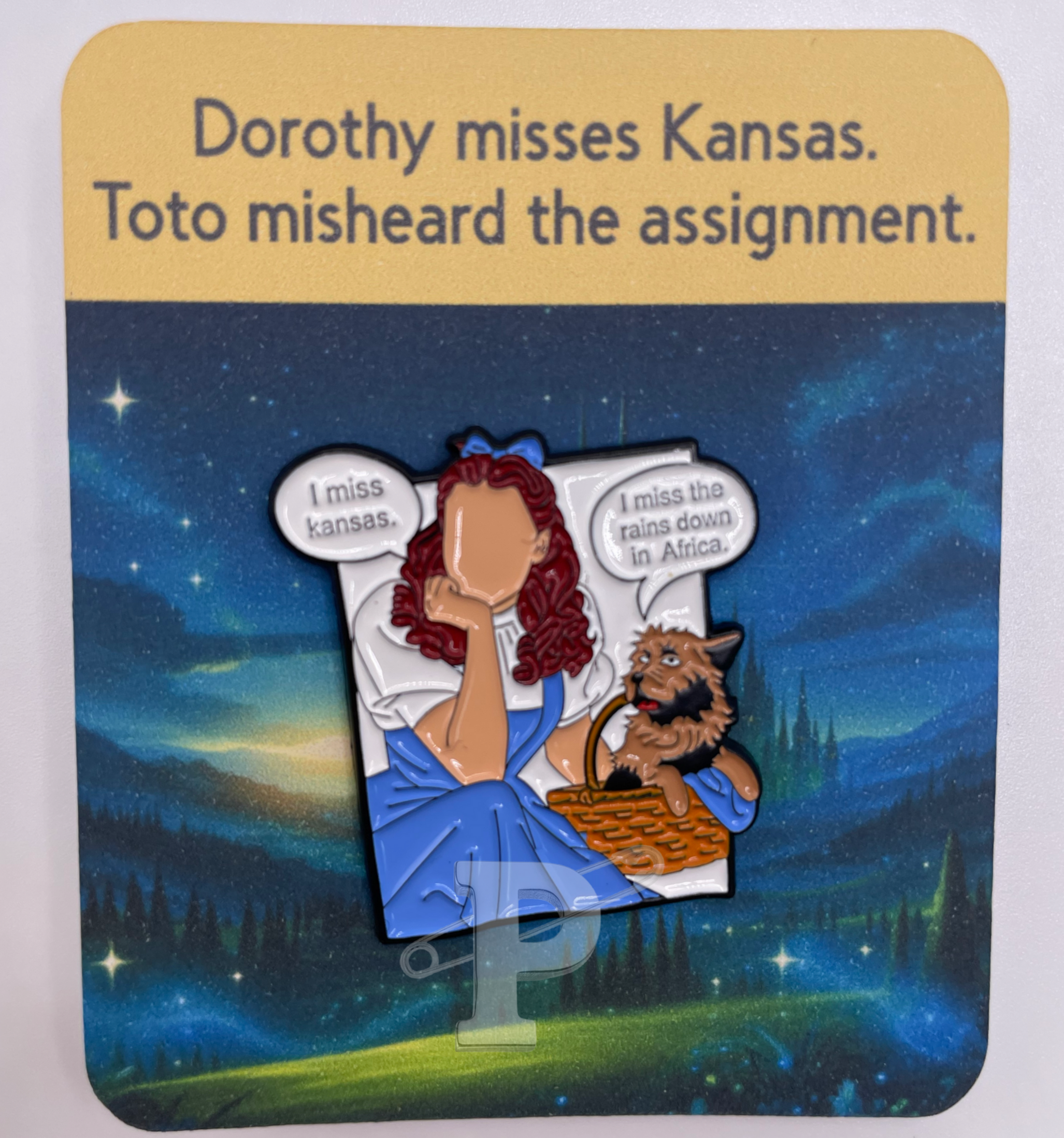 A flat card that says "Dorothy misses Kansas. Toto misheard the assignment." with Dorothy and Toto pin attached.