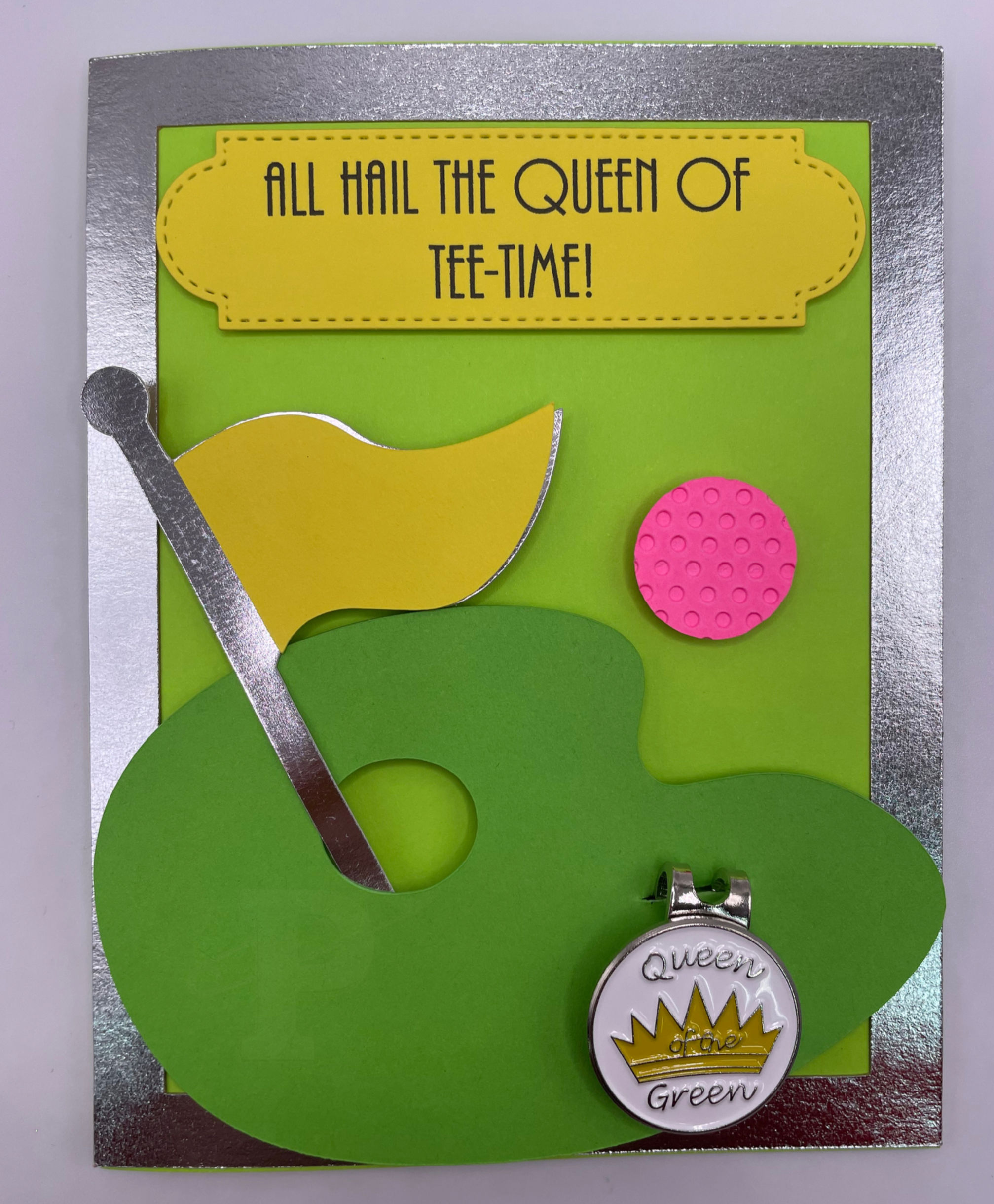 Golf card with “All hail the queen of tee time” and detachable “Queen of the Green” ball marker with hat clip.