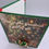 Thumbnail: Top view of card with jeweled present brooch and green bow, set against a glowing Christmas tree with ornaments and lights.