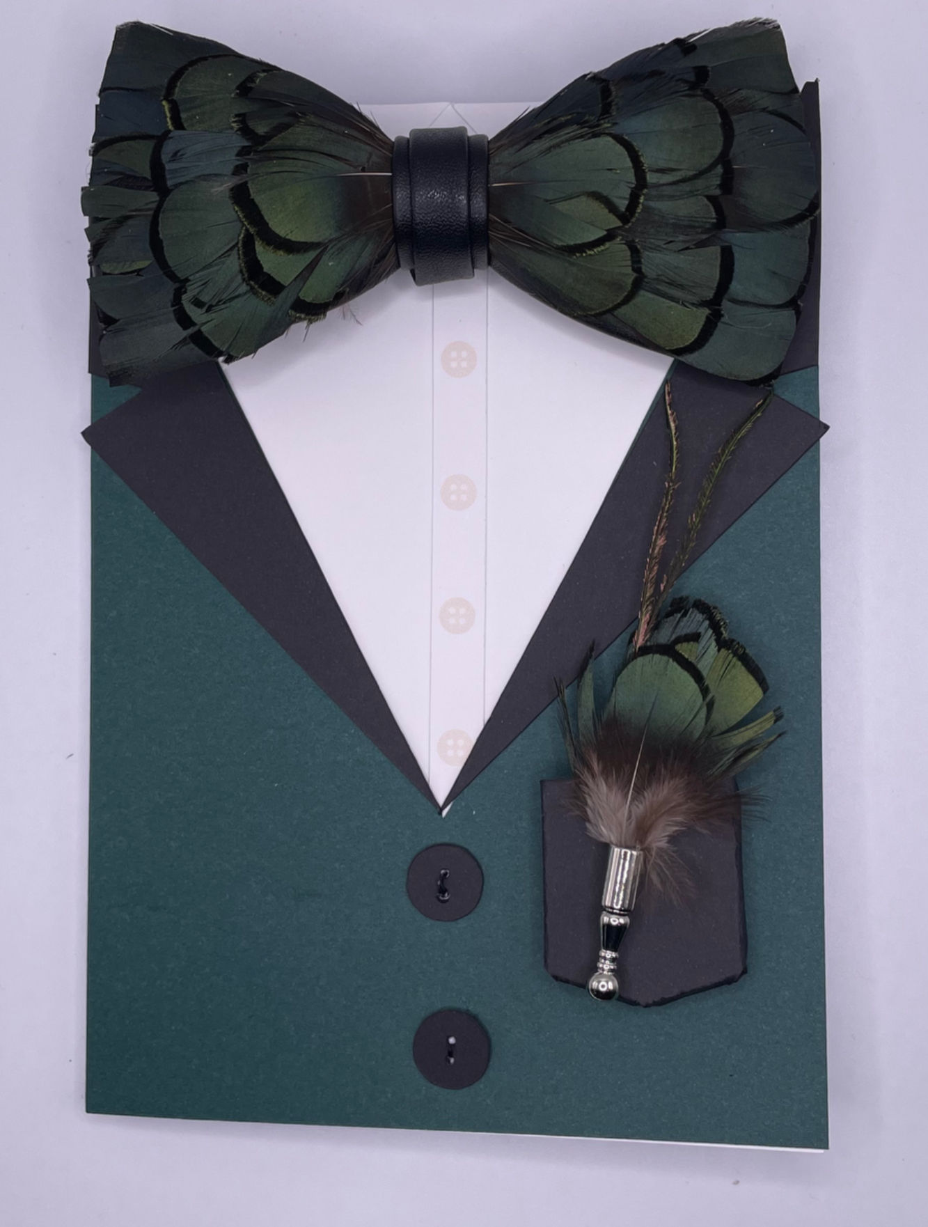 Greeting card shaped like a suit jacket with emerald green background, feather bow tie, and detachable lapel pin