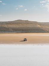 Photographie de véhicule dans un paysage désertique minimaliste, mise en valeur d’un territoire isolé et sauvage