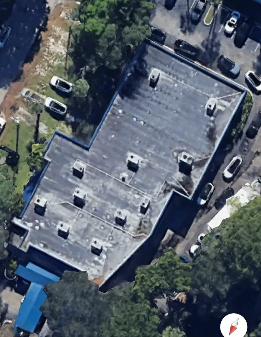 Top-down satellite-style image of a commercial building with a dark flat roof, multiple ro