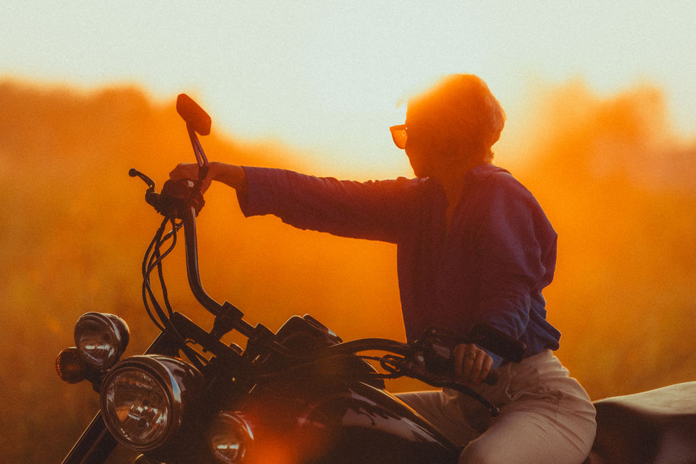a woman is riding a motorcycle at sunset