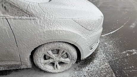 Close up of a car covered in snow foam, symbolizing winter care and vehicle maintenance, s