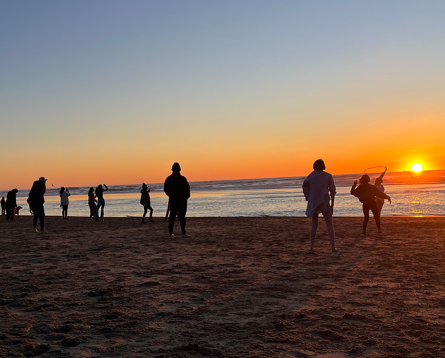 Dancers silhouetted on the sand at Ocean Beach as the sun sets over the Pacific