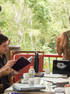A group of artists and members of R.A.R.O. Bogotá gathered around a table in an outdoor space during the Artwork Clinic of the residency.