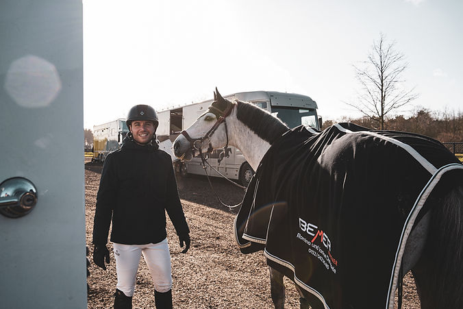 white stallion horse and ride standing in front of an STX Horsetruck