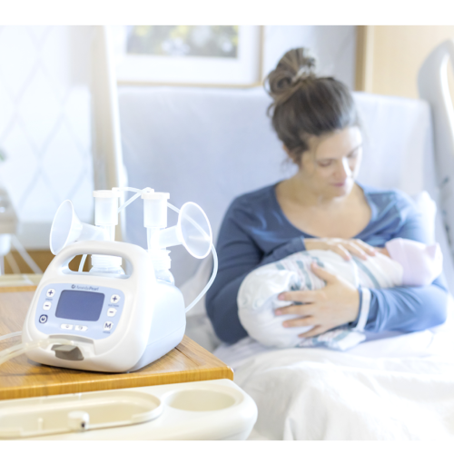 New mother cradles her baby in a hospital room, with an Ameda Pearl hospital-grade breast pump by her side.