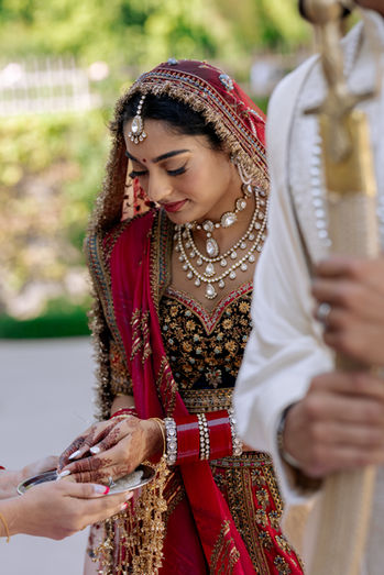 Sikh bride picking up rice with her hands during a traditional wedding ceremony.