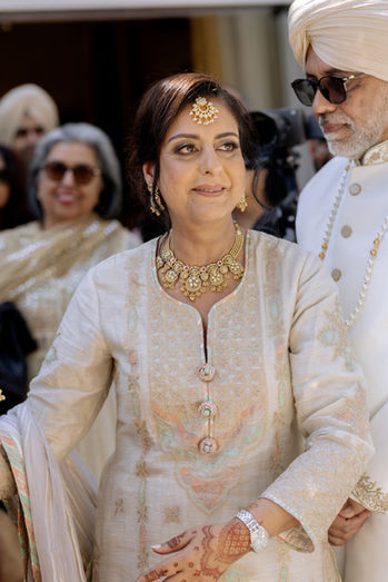 Mother smiling warmly at her daughter, the bride, during a Sikh wedding ceremony.