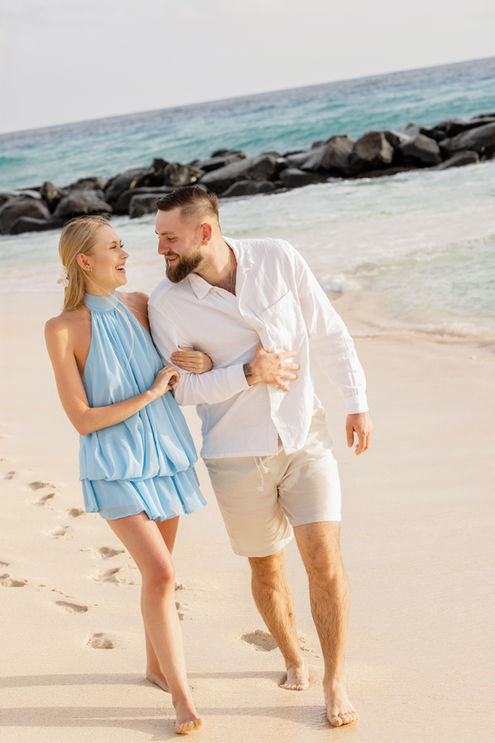 couple walking on the beach in barbados getting photos taken while walking on the beach