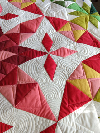 This rainbow quilt was custom quilted with swirls and dot to dot elements.