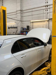 White car being serviced on a 2 post lift