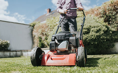 Man mowing the grass with a manual petrol lawnmower..jpg