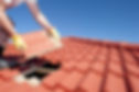 Roof repair, worker with yellow gloves replacing red tiles