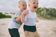 Twin boys laughing at the camera during caves beach family photography session