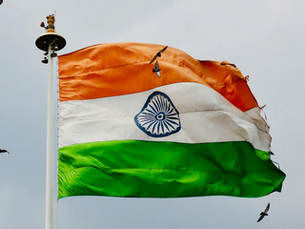 Indian national flag waving against the sky with birds flying around, symbolizing freedom, unity, and the spirit of Independence Day celebrations in the workplace.