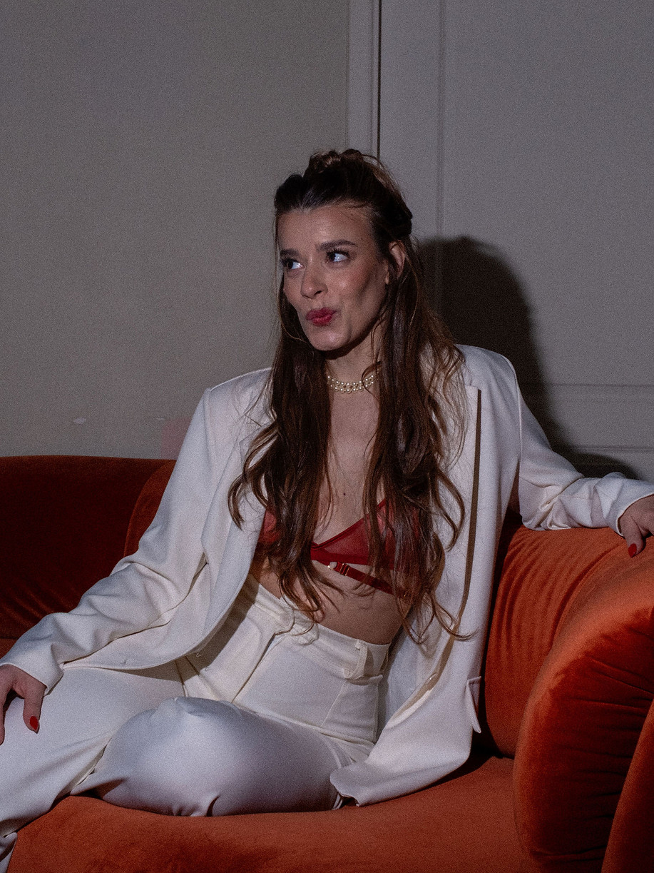 Woman sitting on orange couch posing in professional white suit