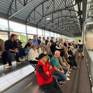 Menschen auf einer Tribüne in einer Turnhalle