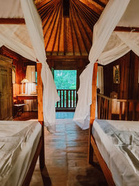 Twin beds with canopy drapes inside Marigold Cottage, Pemuteran.