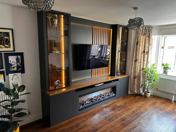 Custom-designed media wall featuring a sleek fireplace, integrated LED lighting, slatwall paneling, and elegant glass elements. The modern and bespoke design seamlessly blends functionality with aesthetics, creating a visually stunning and technologically advanced focal point for the room