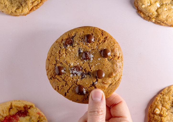 Hand holding a baked chocolate chunk cookie close-up.