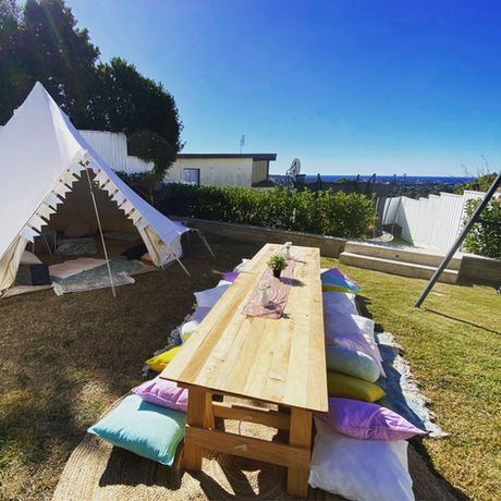 Picnic Table with Decorations and cushions with a bell tent in a backyard