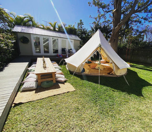 Picnic Table with Decorations and cushions with a bell tent in a backyard