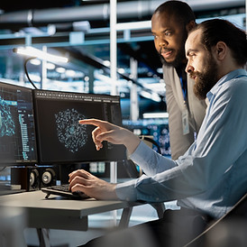 Team of professionals working with complex data systems on multiple screens in a control room.