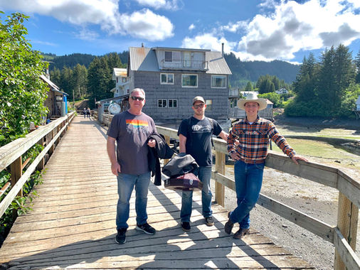 Joey McKenzie, Matthew Mefford, Ridge Roberts standing on a bridge in front of a house in Alaska