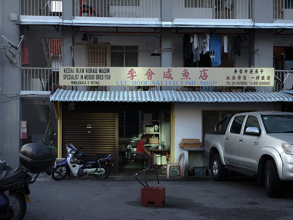 a man reading newspaper inside his shop lot illuminated by pockets of light.