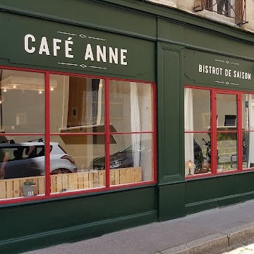 Façade verte d’un café aux vitrines rouges, enseignes CAFÉ ANNE et BISTROT DE SAISON, ambiance calme.