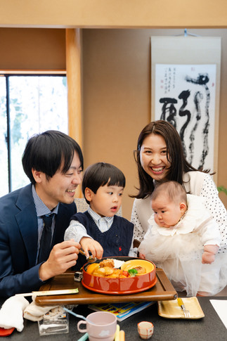 料理を見つめる赤ちゃんとの和やかな家族写真