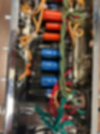 Close-up view of the interior components of a guitar amplifier, showcasing wires, circuit boards, and tubes.