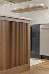 Close-up of fluted wood kitchen island cabinetry with white oak shelving and marble countertop