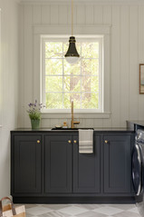 Custom navy laundry room cabinetry with brass pendant light and gold hardware by Sprague Interiors
