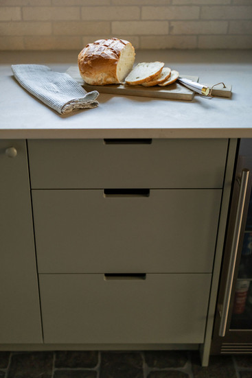 sage green kitchen drawer bank with bread on marble counter